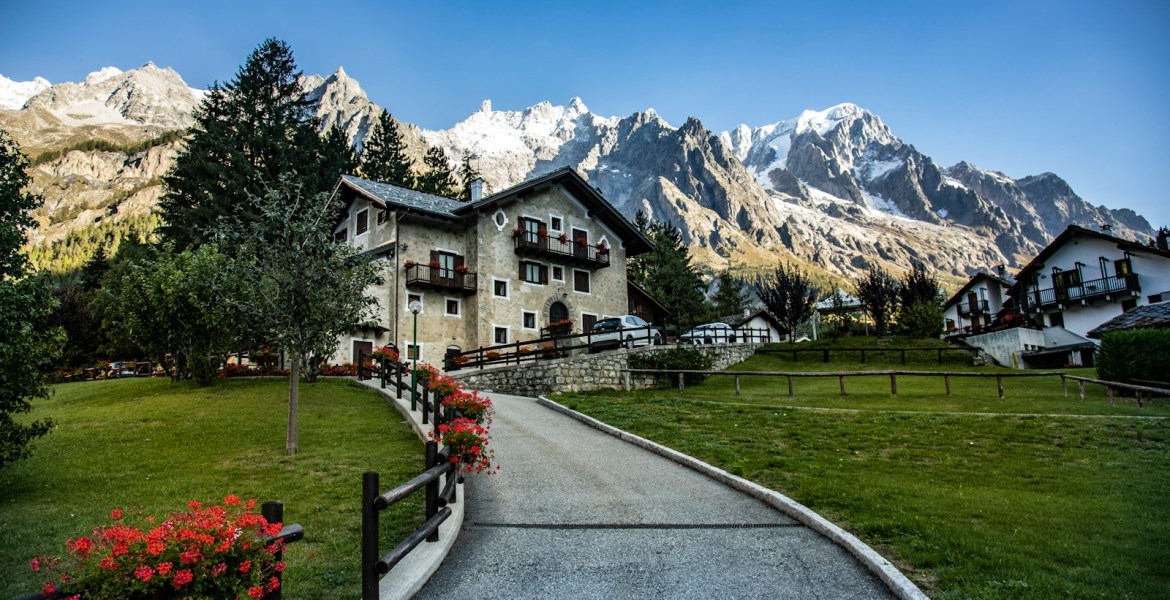 a road leading to a house with mountains in the background