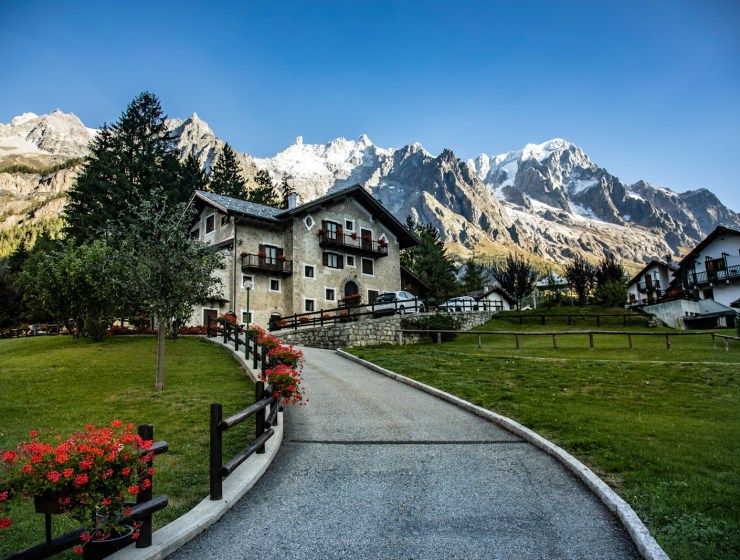 a road leading to a house with mountains in the background