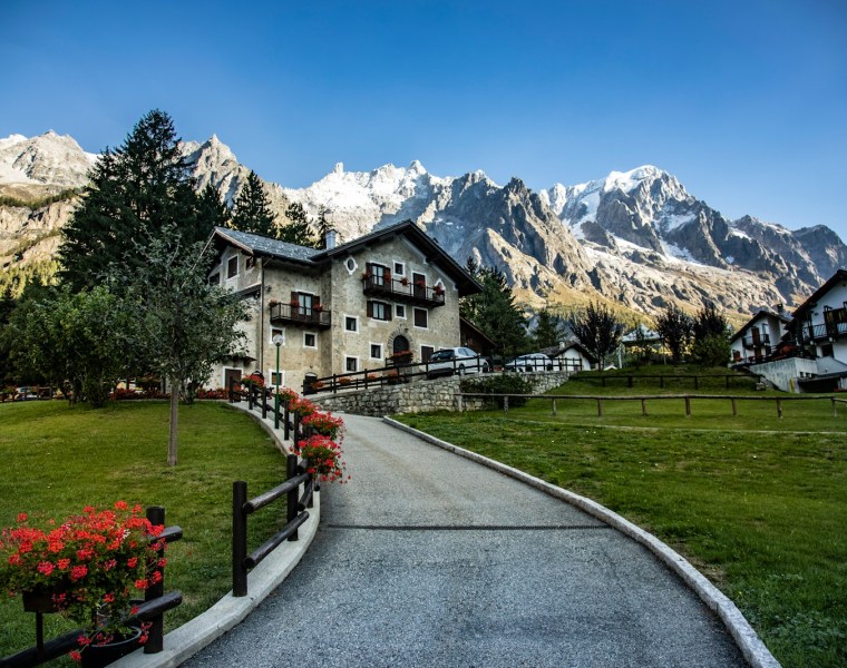 a road leading to a house with mountains in the background