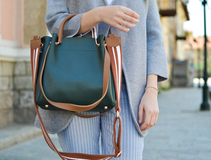 women standing while carrying green and brown leather 2-way shoulder bag