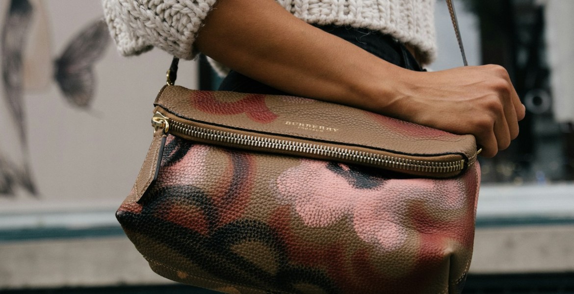 woman holding brown and pink floral leather crossbody bag