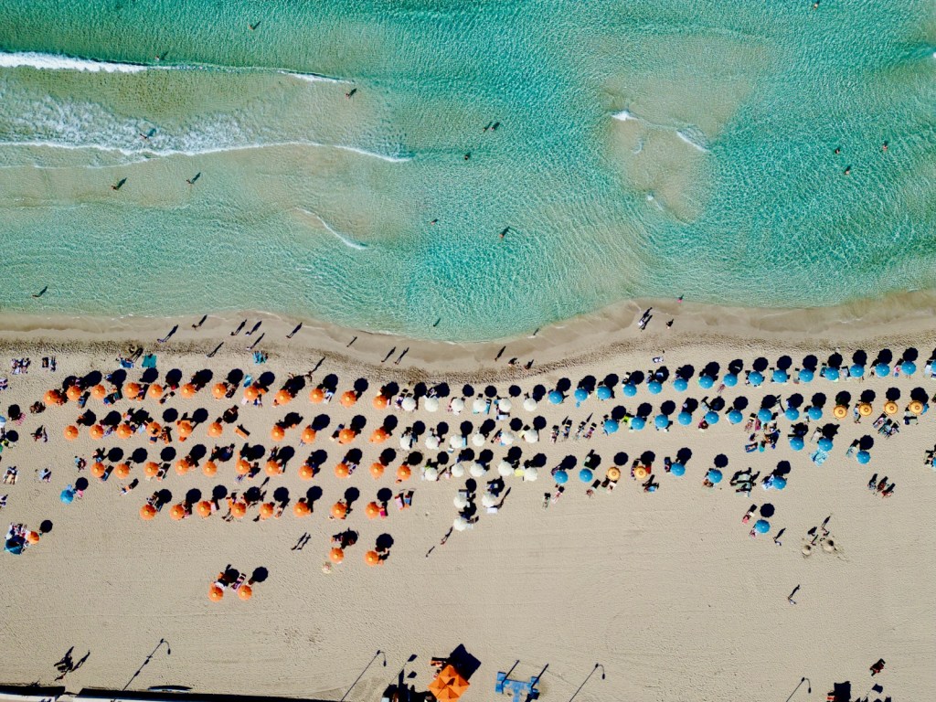 An aerial view of a beach with umbrellas and chairs