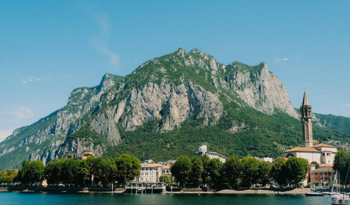 a large mountain with a building on it by a body of water