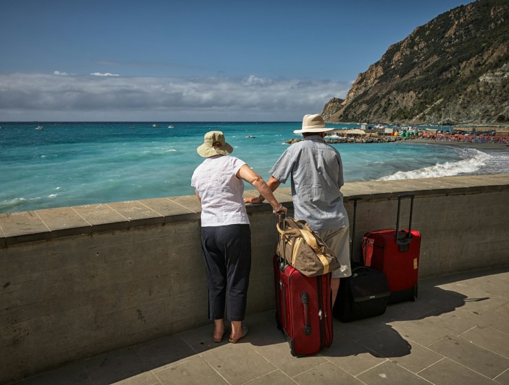 man and woman standing beside concrete seawall looking at beach