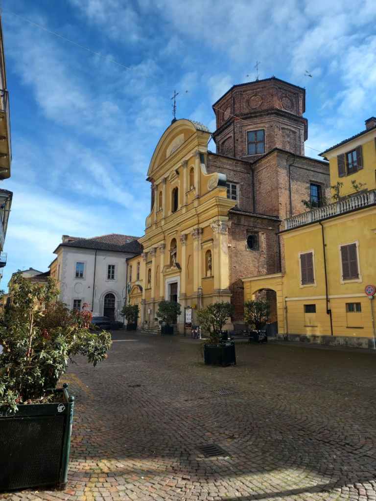 Scenic view of a historic church in Asti, Piedmont, Italy under a bright blue sky.