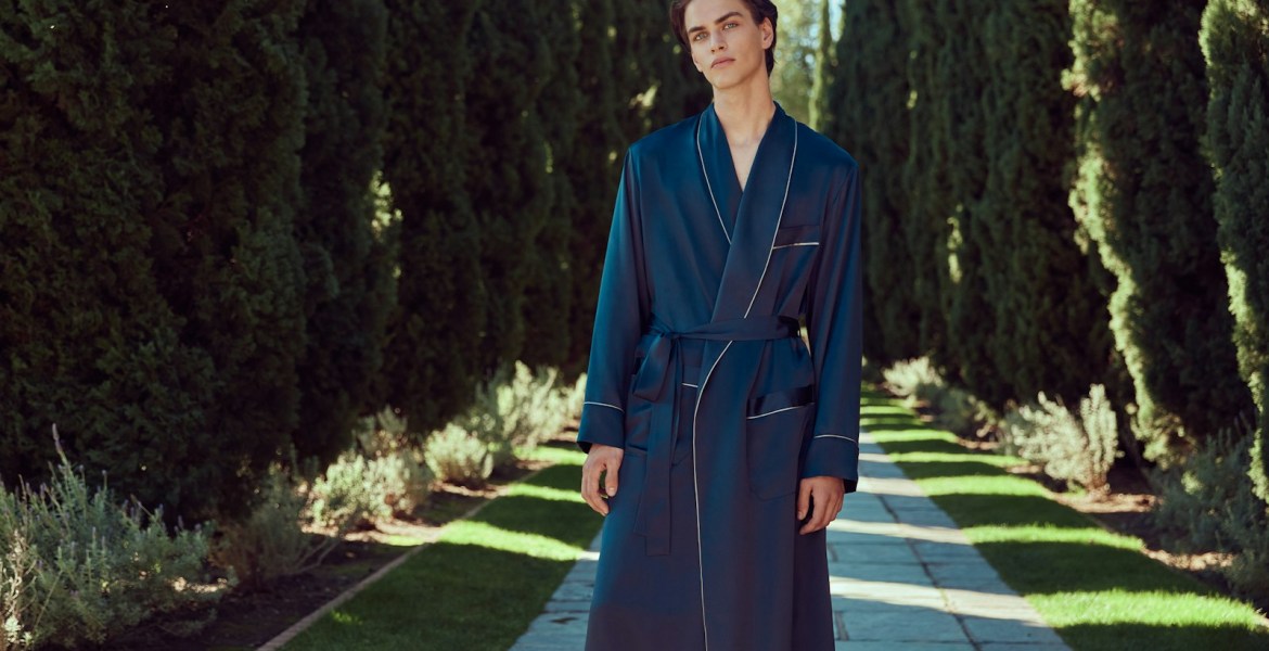 A man stands wearing a dark blue robe.