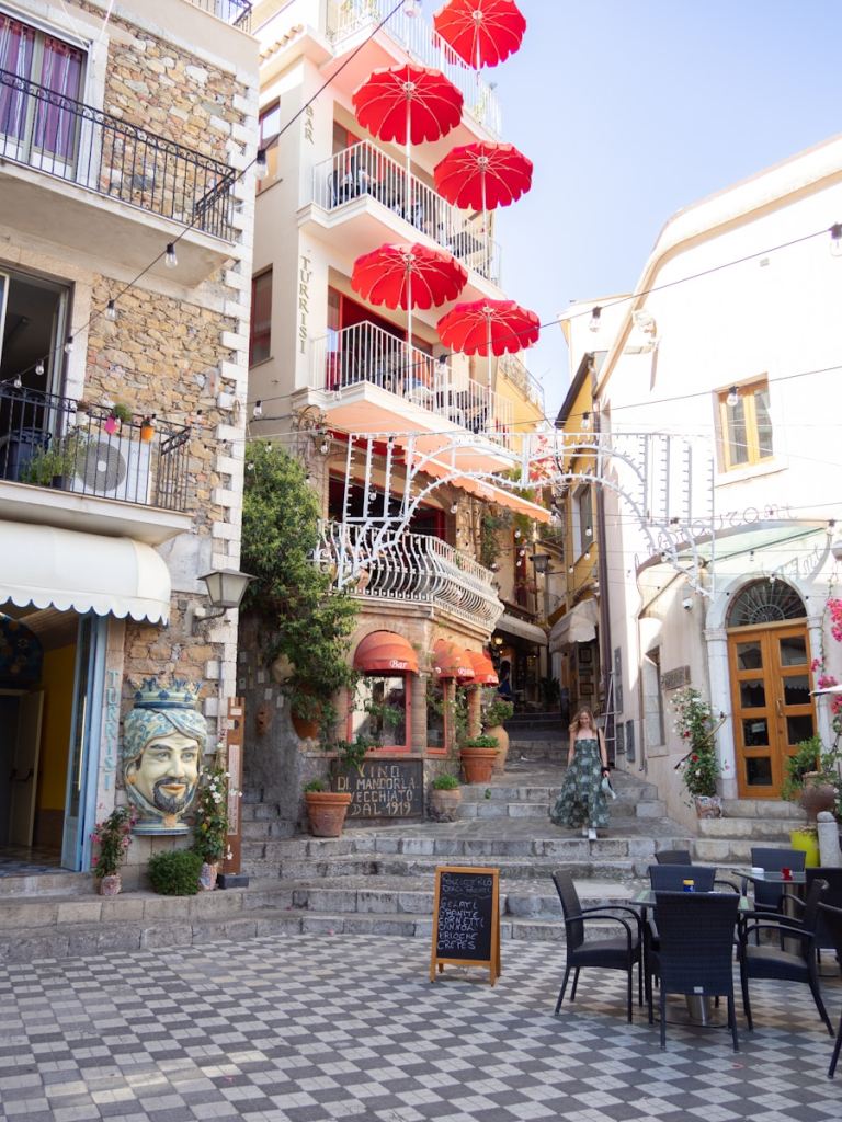 a group of red umbrellas hanging from the side of a building