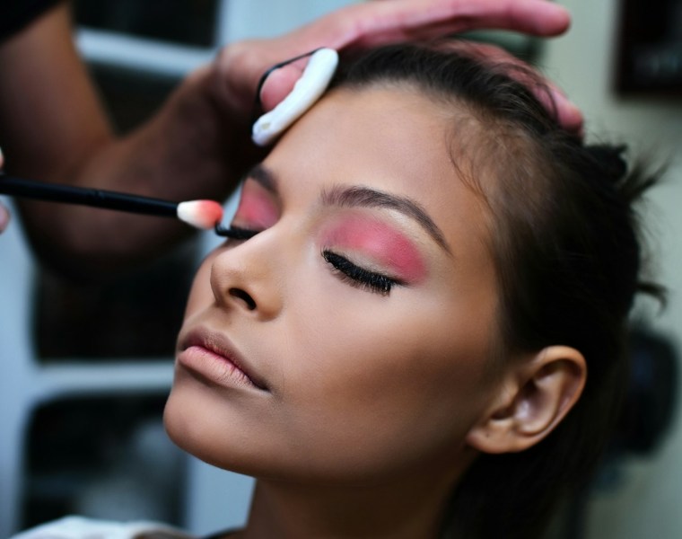 woman with pink lipstick holding white and purple toothbrush
