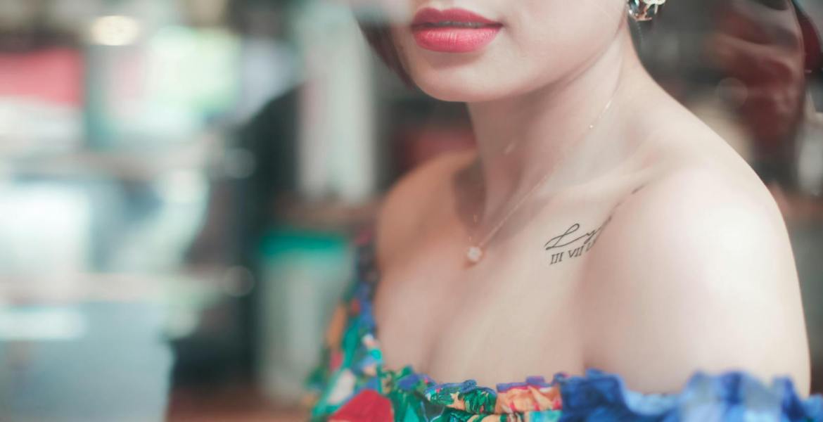 Close-up of a woman in vibrant fashion with a shoulder tattoo.
