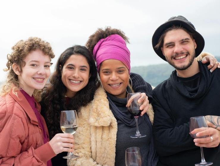 A diverse group of friends enjoying wine together outdoors, smiling and celebrating friendship.