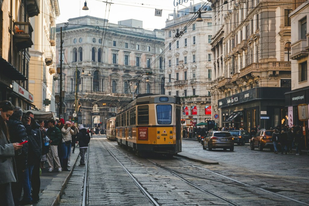 Un treno giallo che viaggia lungo una strada accanto a edifici alti