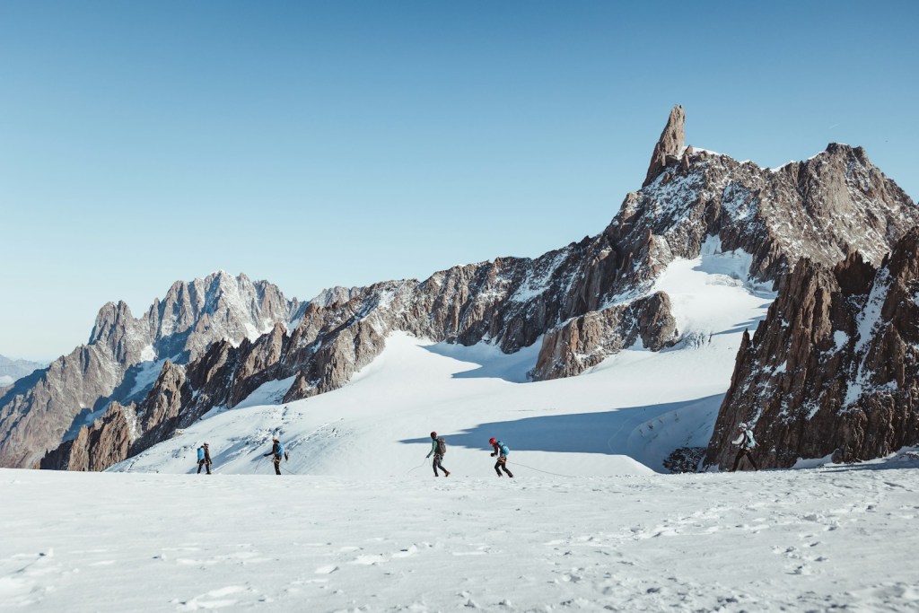 a group of people skiing down a snow covered mountain in Courmayeur