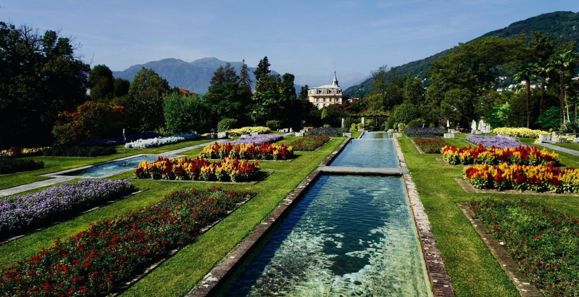 a garden filled with lots of flowers next to a river
