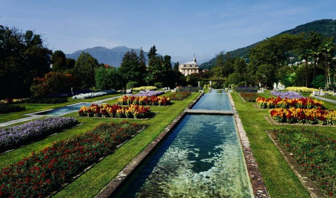 a garden filled with lots of flowers next to a river