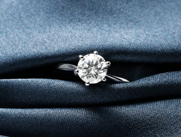 A close up of a diamond ring on a blue cloth