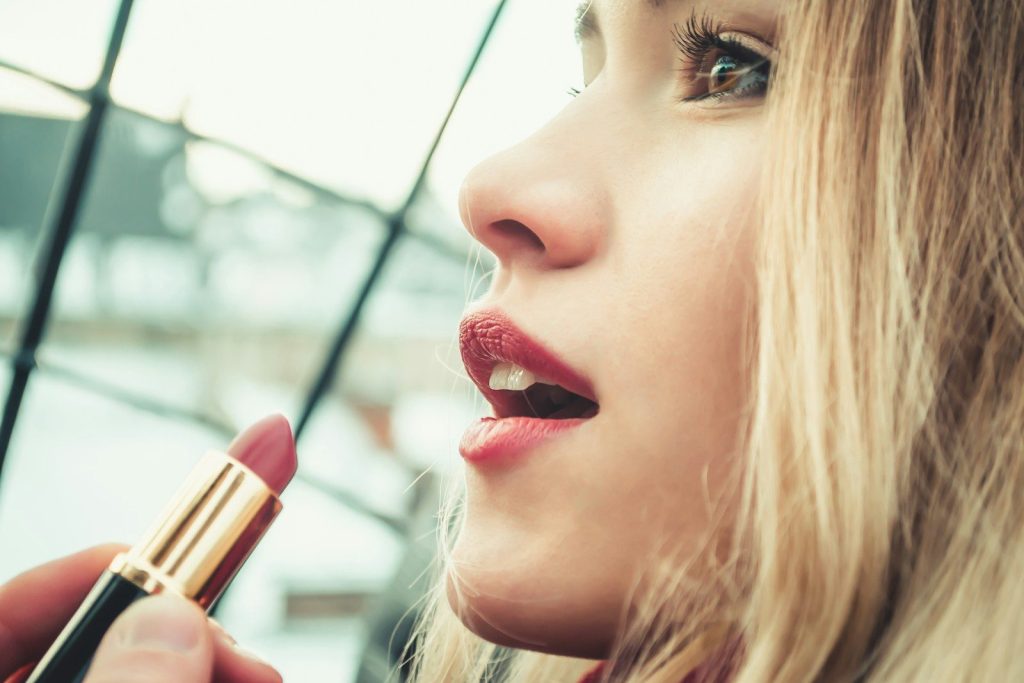 fotografia con messa a fuoco selettiva di una donna che tiene il rossetto