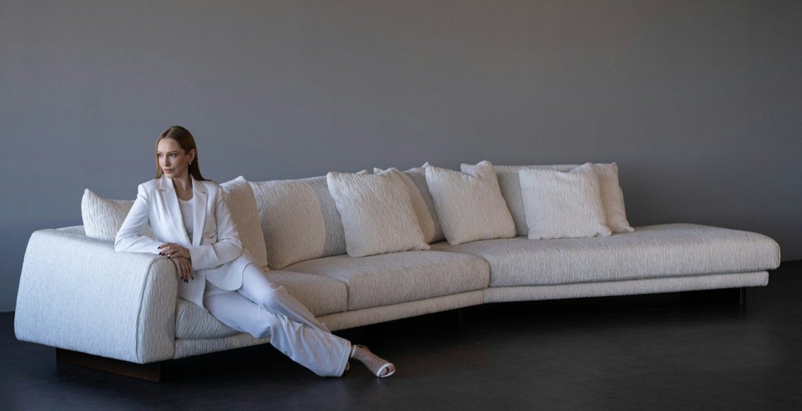 Woman in white suit sitting on a modern white sofa.
