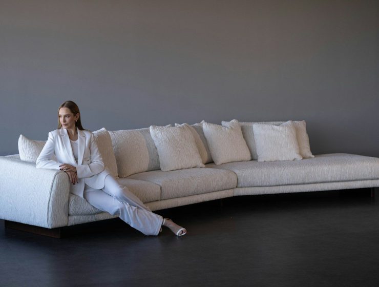 Woman in white suit sitting on a modern white sofa.