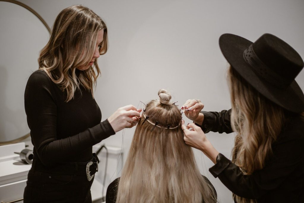 a hairdresser working on a client getting halo hair extensions styled 