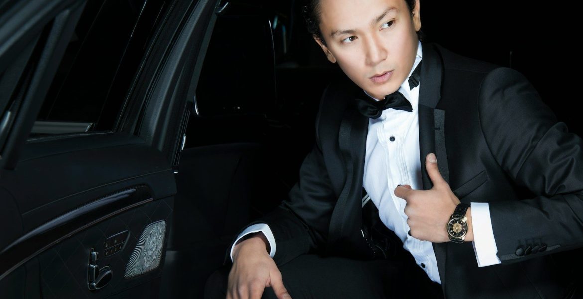 man in black blazer sits inside the car