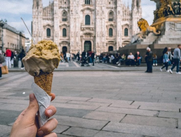 a hand holding an ice cream cone in front of a cathedral