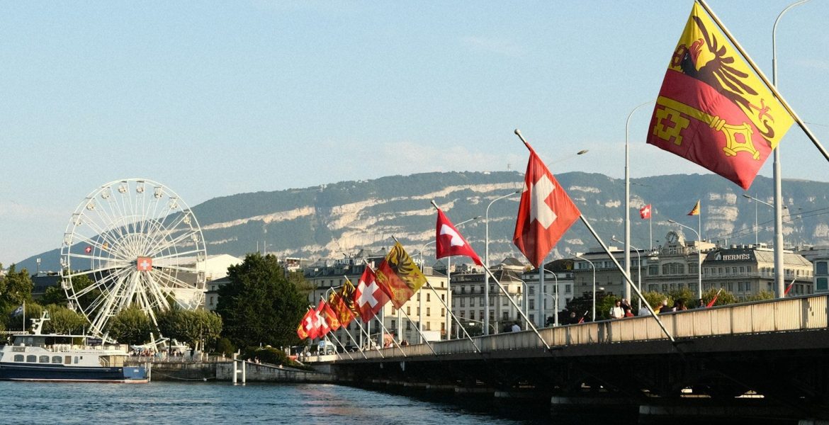 A body of water with a bridge and a ferris wheel in the background, Geneva Switzerland