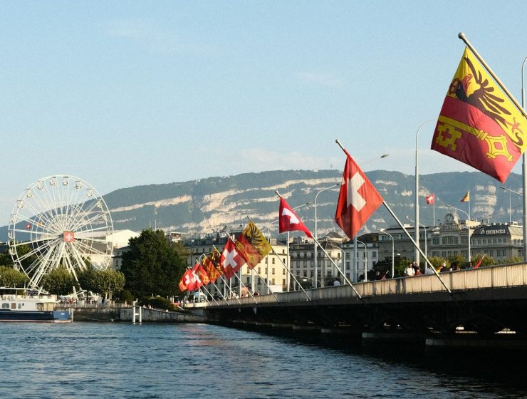 A body of water with a bridge and a ferris wheel in the background, Geneva Switzerland