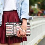 woman holding clutch bag standing beside white bridge