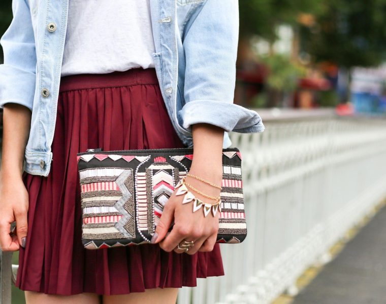 woman holding clutch bag standing beside white bridge