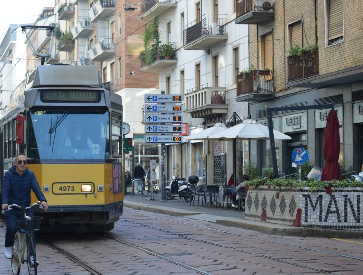 A man riding a bike down a street next to a train