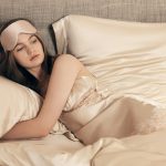 A woman lies in bed, wearing a sleep mask